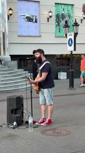 Acoustic street performance on a Kazan sidewalk, summer 2026.