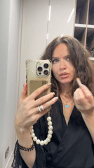 Woman applies makeup using phone camera in Khimki bedroom