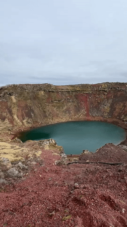 Tourists visit Kerið crater lake under overcast skies