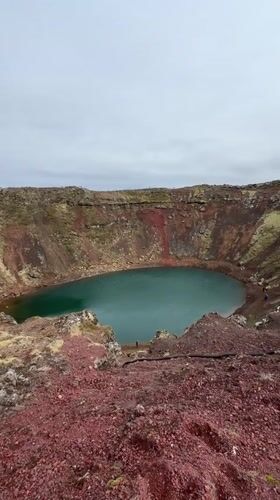 Tourists visit Kerið crater lake under overcast skies