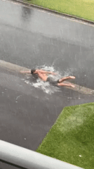 Person swims in flooded streets during heavy rainfall in Bulli
