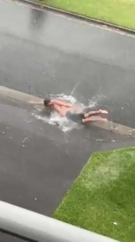 Person swims in flooded streets during heavy rainfall in Bulli