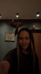 Woman cleans house with parrot perched on head