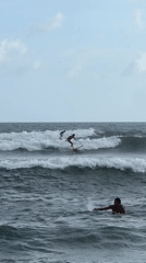 Three people surf and swim in North Kuta waters