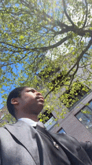 Person in suit makes kissing gesture at tree in London
