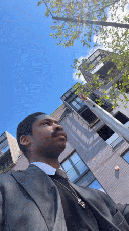 Person in suit makes kissing gesture at tree in London