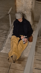 Young person sits on concrete platform near stairwell