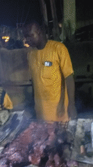 Man prepares traditional suya meat outdoors in Nigeria
