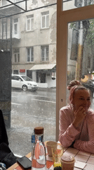 Woman sits in Tbilisi cafe during heavy rainstorm