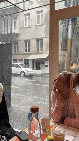 Woman sits in Tbilisi cafe during heavy rainstorm