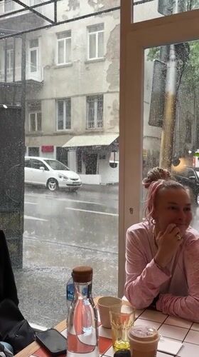Woman sits in Tbilisi cafe during heavy rainstorm