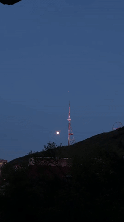 Full moon observed over illuminated Tbilisi TV Tower