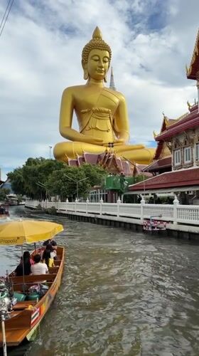 Bangkok temple visitors document golden Buddha statues and canal scenes