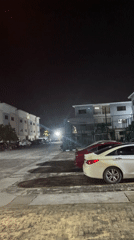 Nighttime parking lot scene captured with streetlit cars, buildings