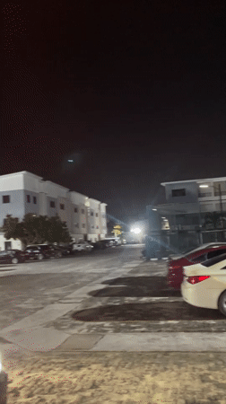 Nighttime parking lot scene captured with streetlit cars, buildings