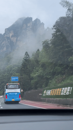 Morning traffic navigates foggy mountain highway in Xiehe, China