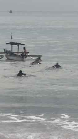 Evening beach activities continue under overcast skies in Kuta
