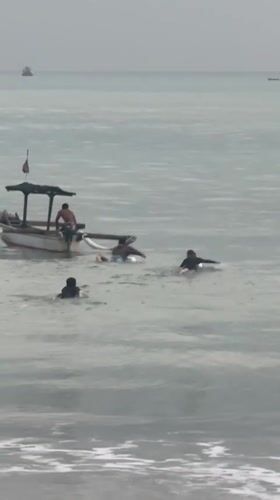 Evening beach activities continue under overcast skies in Kuta