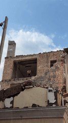 Brick building mid-demolition in Tbilisi under cloudy skies