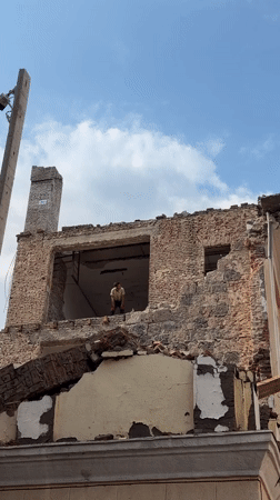 Brick building mid-demolition in Tbilisi under cloudy skies