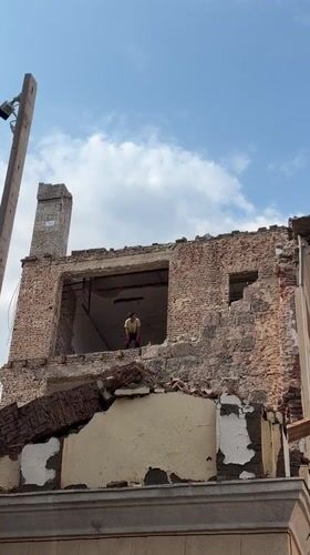Brick building mid-demolition in Tbilisi under cloudy skies