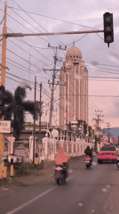 Rainy day traffic flows past distinctive domed building in Indonesia
