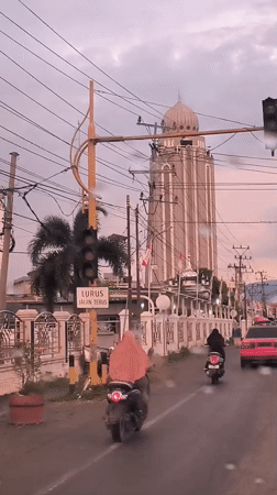 Rainy day traffic flows past distinctive domed building in Indonesia