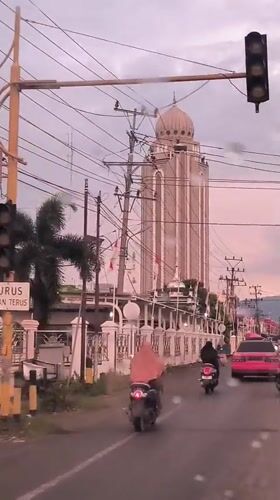 Rainy day traffic flows past distinctive domed building in Indonesia