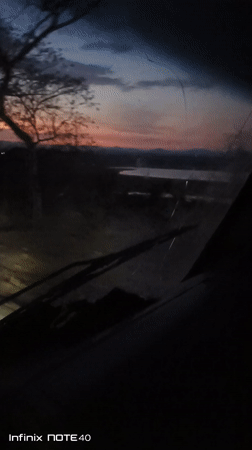 Vehicle travels Venezuelan road at twilight, colorful sky visible