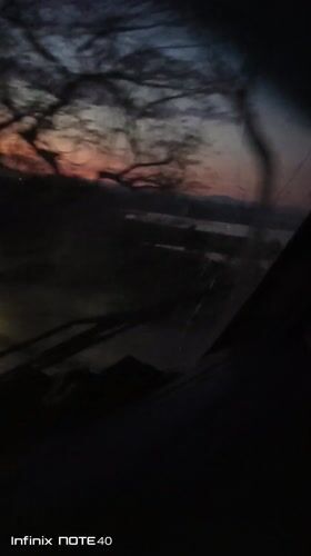 Vehicle travels Venezuelan road at twilight, colorful sky visible