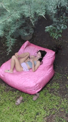 Woman relaxes on pink bean bag in North Kuta garden