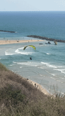 Paramotorists fly over busy Netanya beach during afternoon recreation