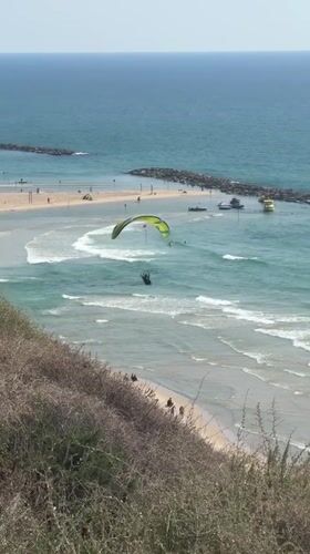 Paramotorists fly over busy Netanya beach during afternoon recreation