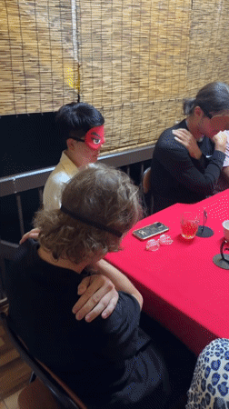 Blindfolded group activity observed around red table in Chiang Mai