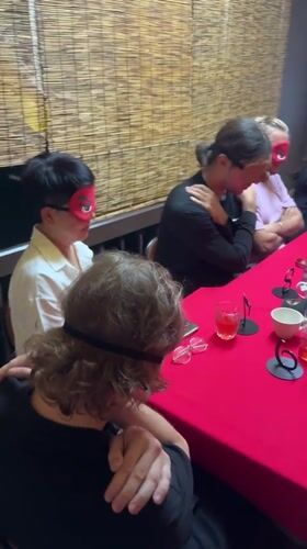 Blindfolded group activity observed around red table in Chiang Mai