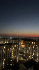 Almaty skyline glows at dusk, apartments lit against a gradient sky