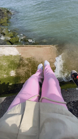 Two people sit on seaside barrier in Old Colwyn