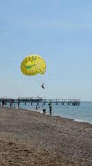 Parasailer glides over calm Turkish coast beneath yellow cartoon parachute
