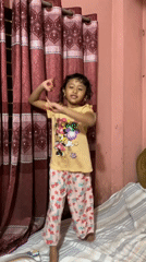 Child plays and dances indoors in Dhaka home