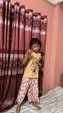 Child plays and dances indoors in Dhaka home