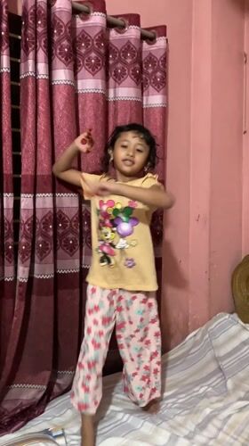 Child plays and dances indoors in Dhaka home