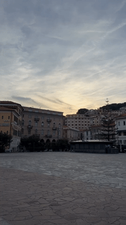 Woman takes selfie in Sanremo piazza under cloudy skies