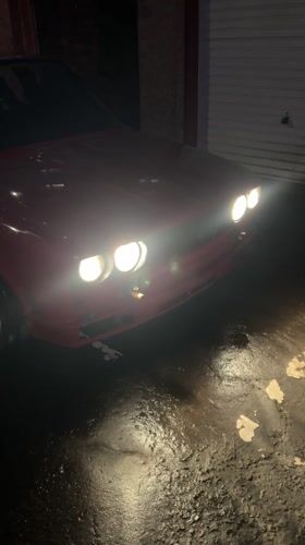 Red car parked with lights on in Glasgow residential area