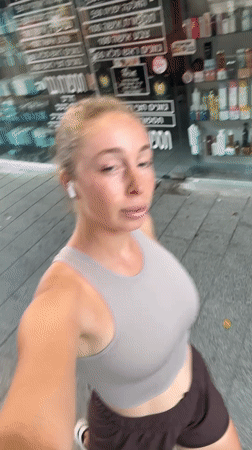 Selfie video moment in Tel Aviv, earbuds in, casual outfit.