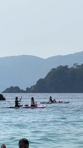 Busy beach day in Fethiye features swimming, boating, paragliding activities