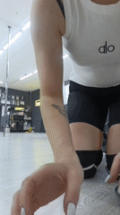 Woman practices pole dancing in studio wearing athletic gear