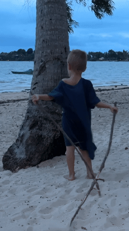 Child plays with sticks on Ko Phangan beach