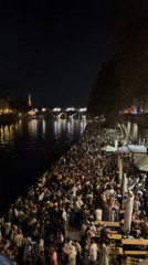 Crowds gather along Seine riverbank in Paris evening