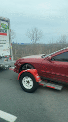 Burgundy Integra towed by U-Haul truck on highway