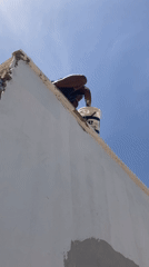 Worker paints building exterior in Jos alleyway